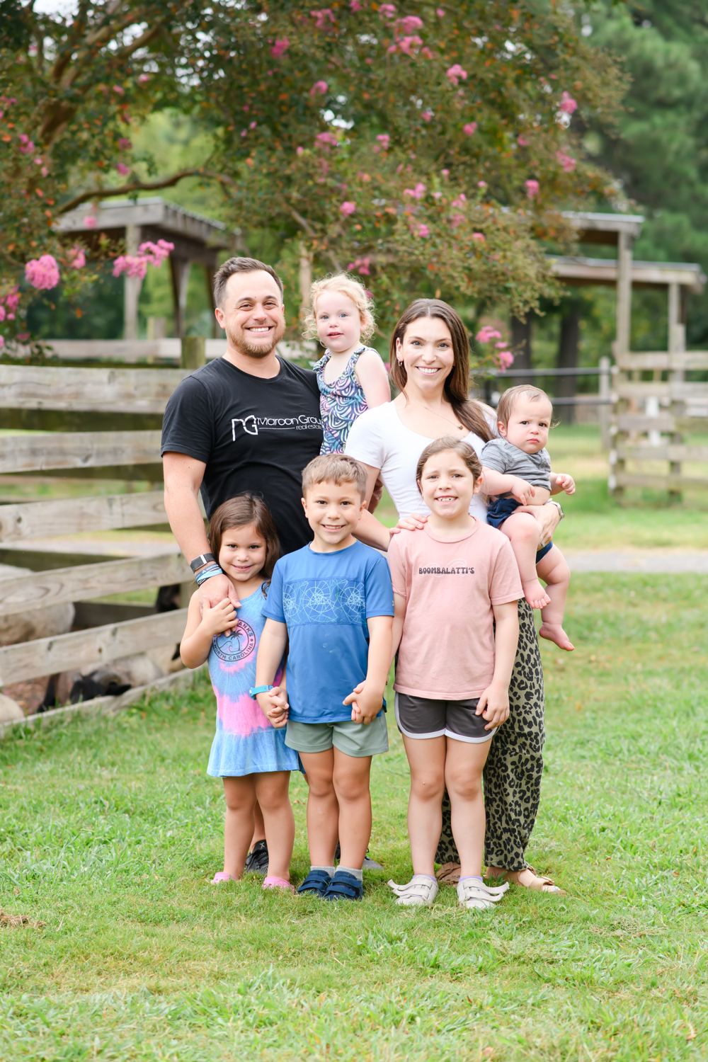 The Maroon family standing together outdoors by a wooden fence